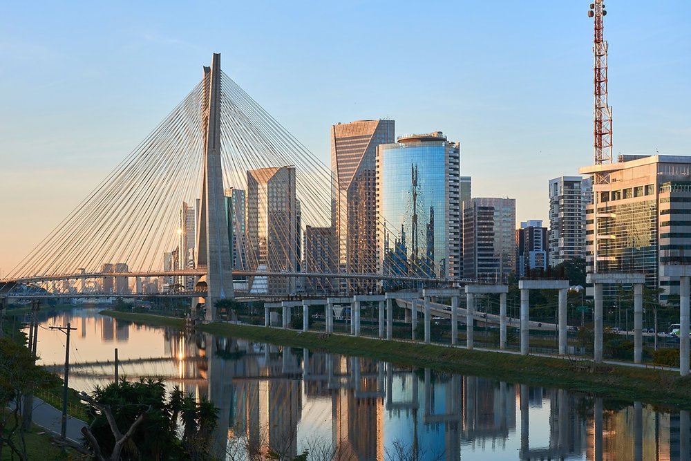 Ponte estaiada e edifícios de São Paulo refletidos no rio, cidade destino de quem vai morar na capital paulista