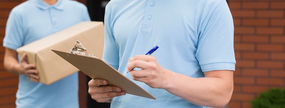Profissional de mudanças conferindo checklist com caixa nas mãos antes do embarque internacional