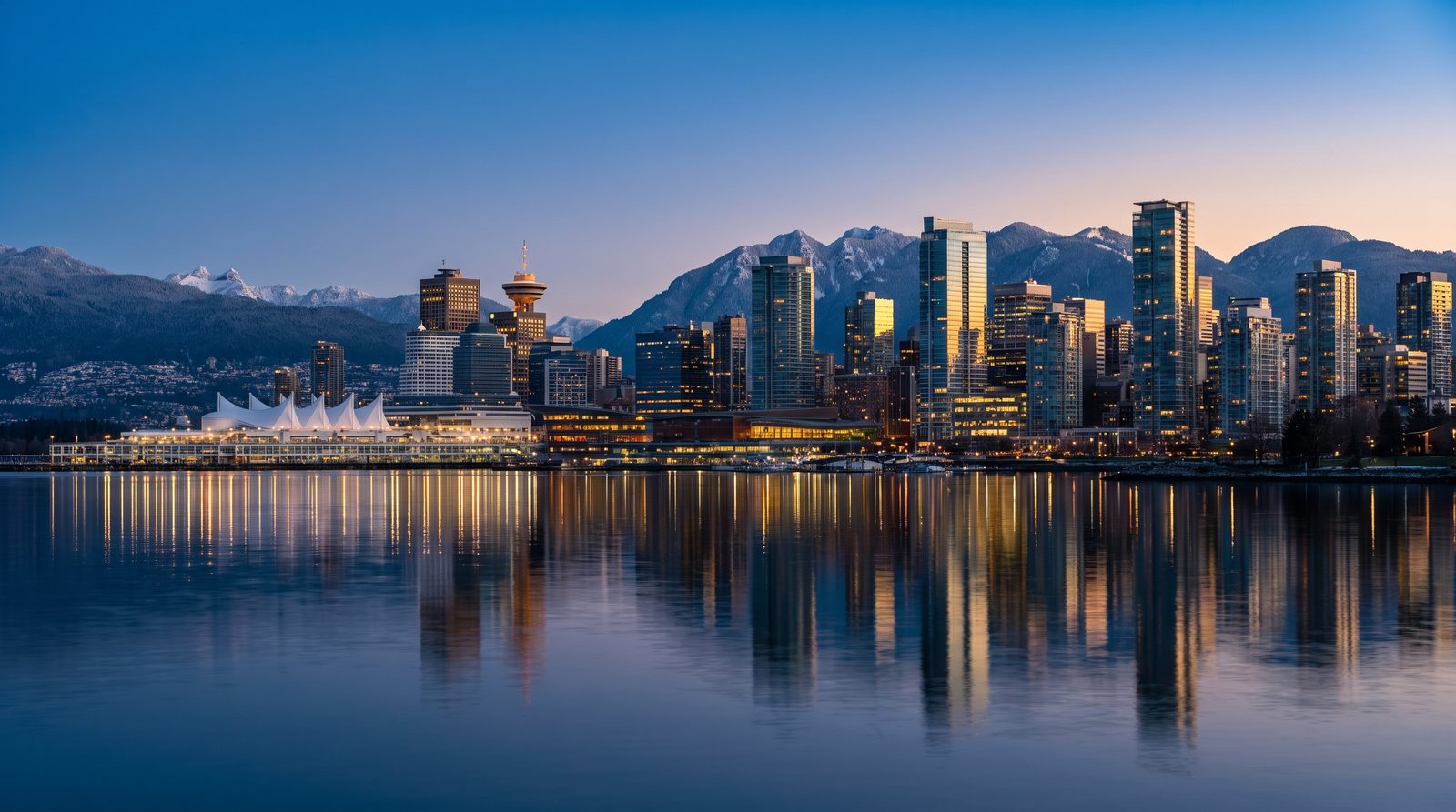 Skyline de Vancouver ao anoitecer com as montanhas nevadas ao fundo, destino de brasileiros que vão imigrar para o Canadá