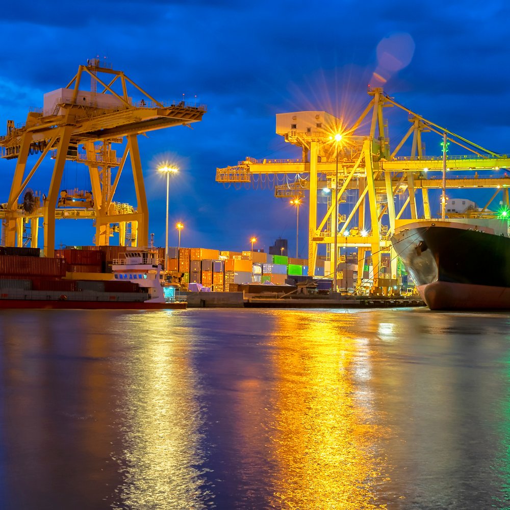 Pórticos e navio iluminados no terminal portuário à noite, saída temporária de bagagem e veículos do país